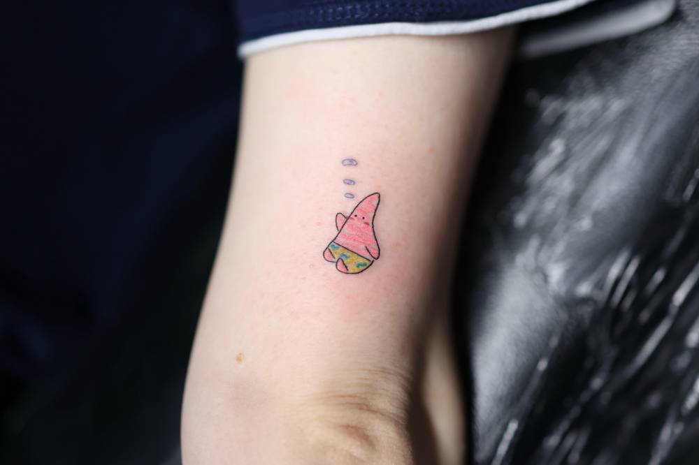 Cartoon style Patrick Star tattoo located on the tricep.