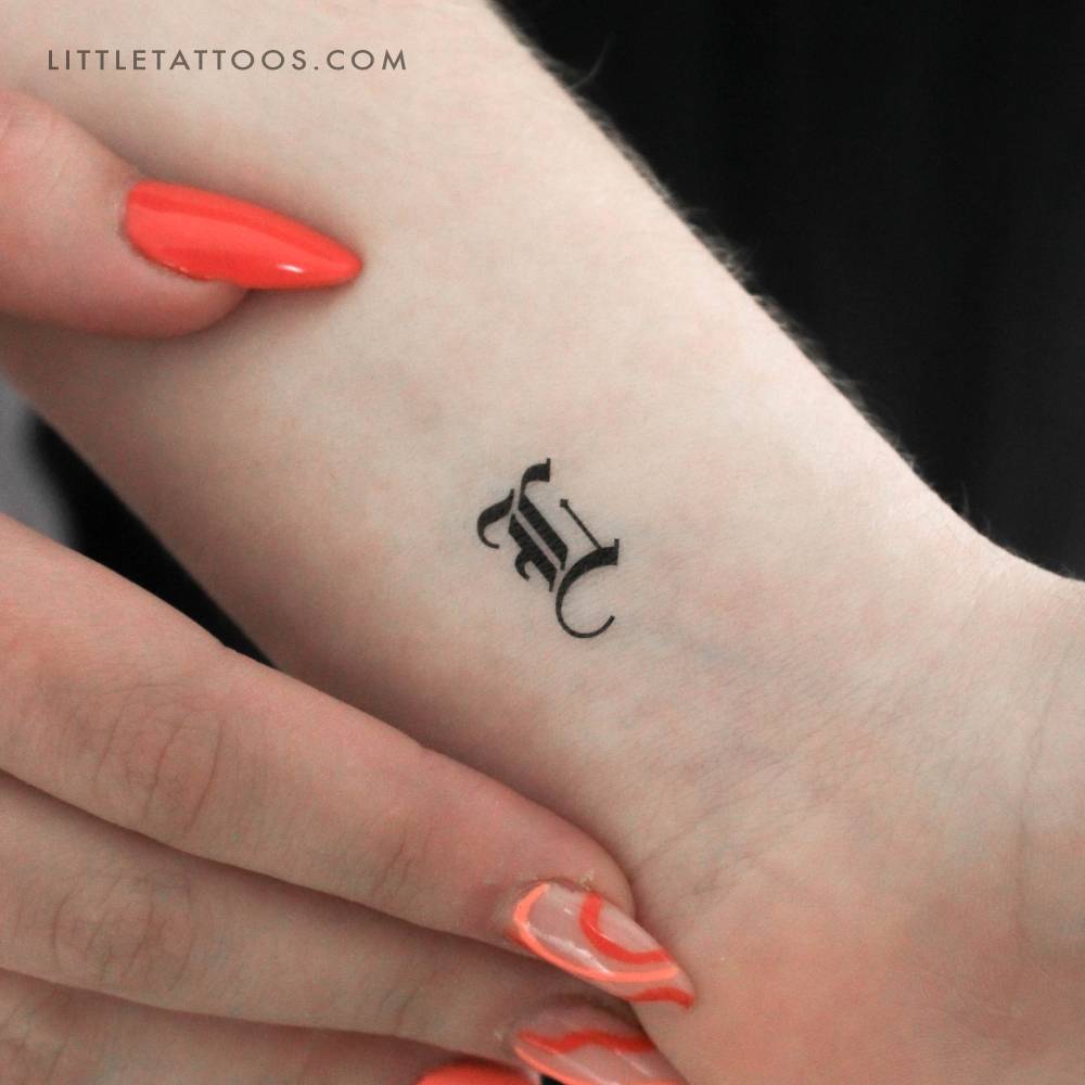 Gothic font "L" letter temporary tattoo located on the wrist.