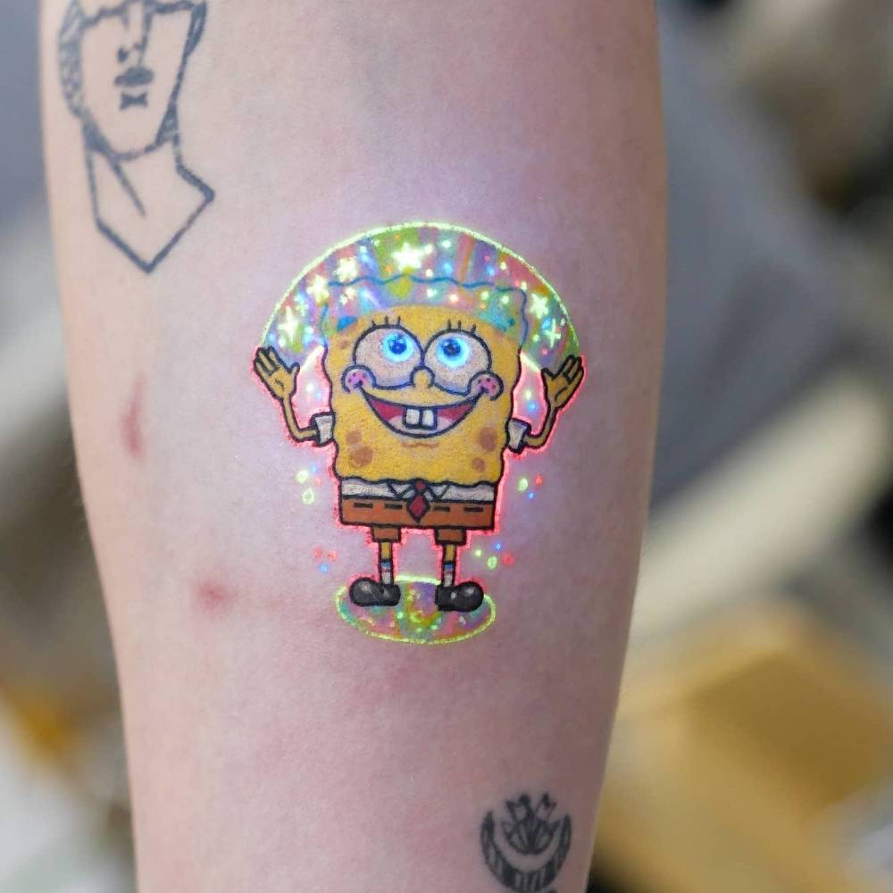 Cartoon style Spongebob tattoo in UV ink located on the inner forearm.