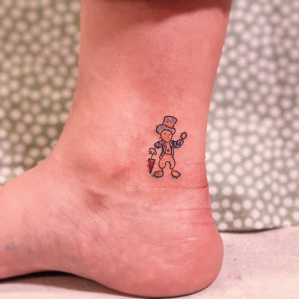 Jiminy Cricket tattoo located on the ankle, cartoon style.