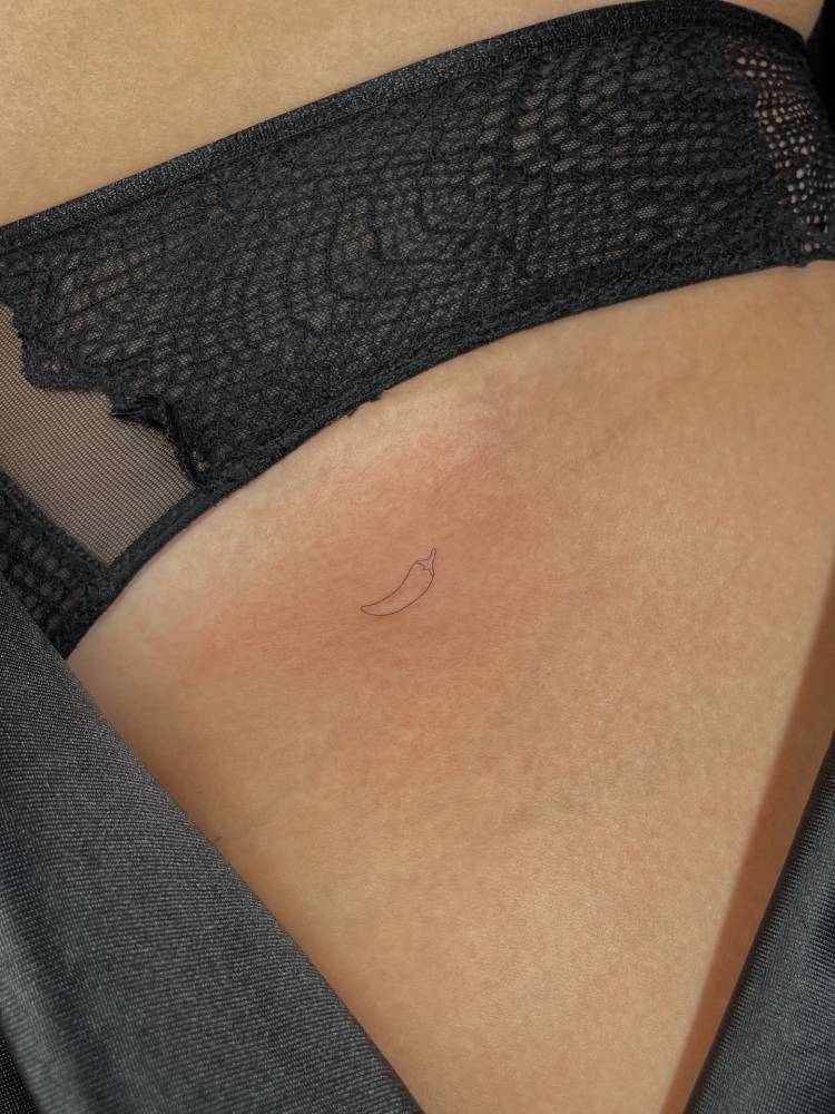 Tiny minimalistic red chili pepper tattoo placed on the pelvis.