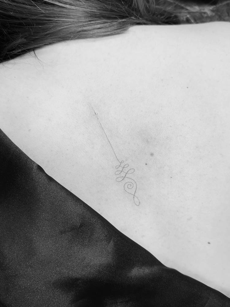 Unalome tattoo done on the upper back, fine line style.