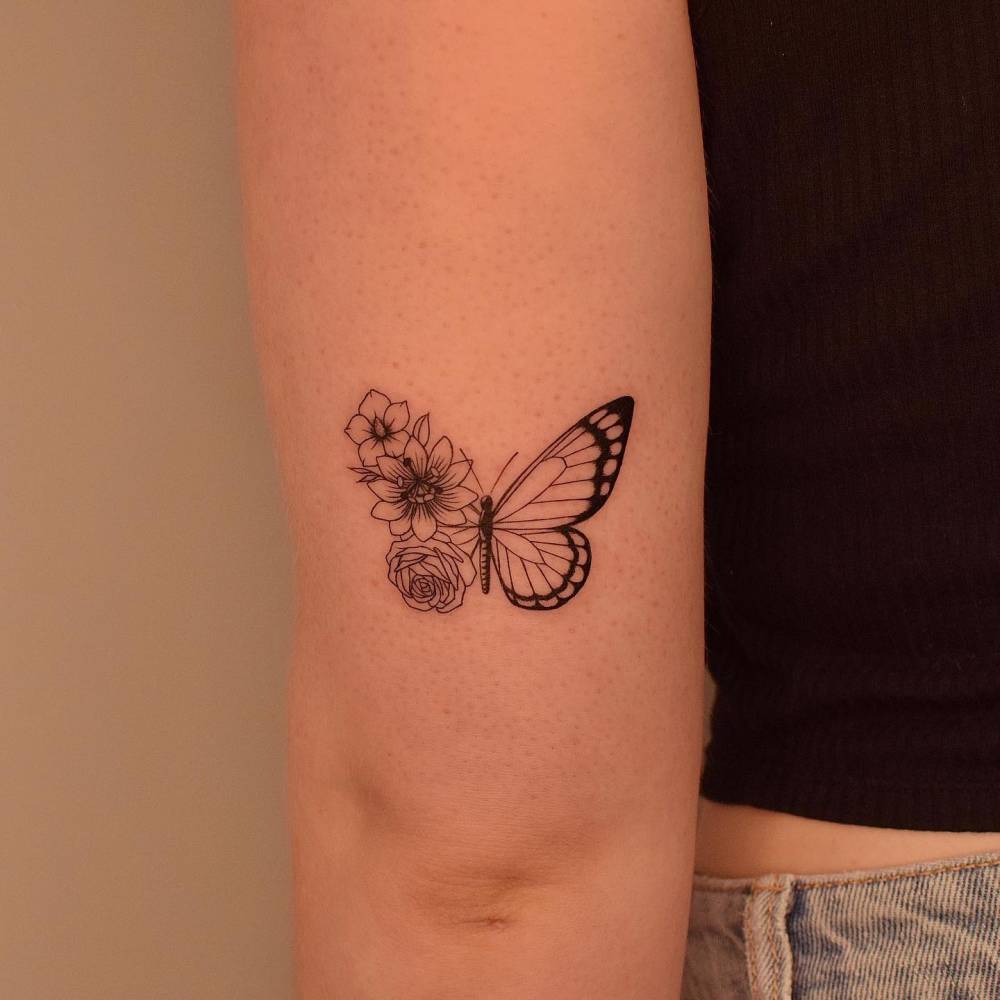 Half butterfly half flower tattoo located on the tricep, illustrative style.
