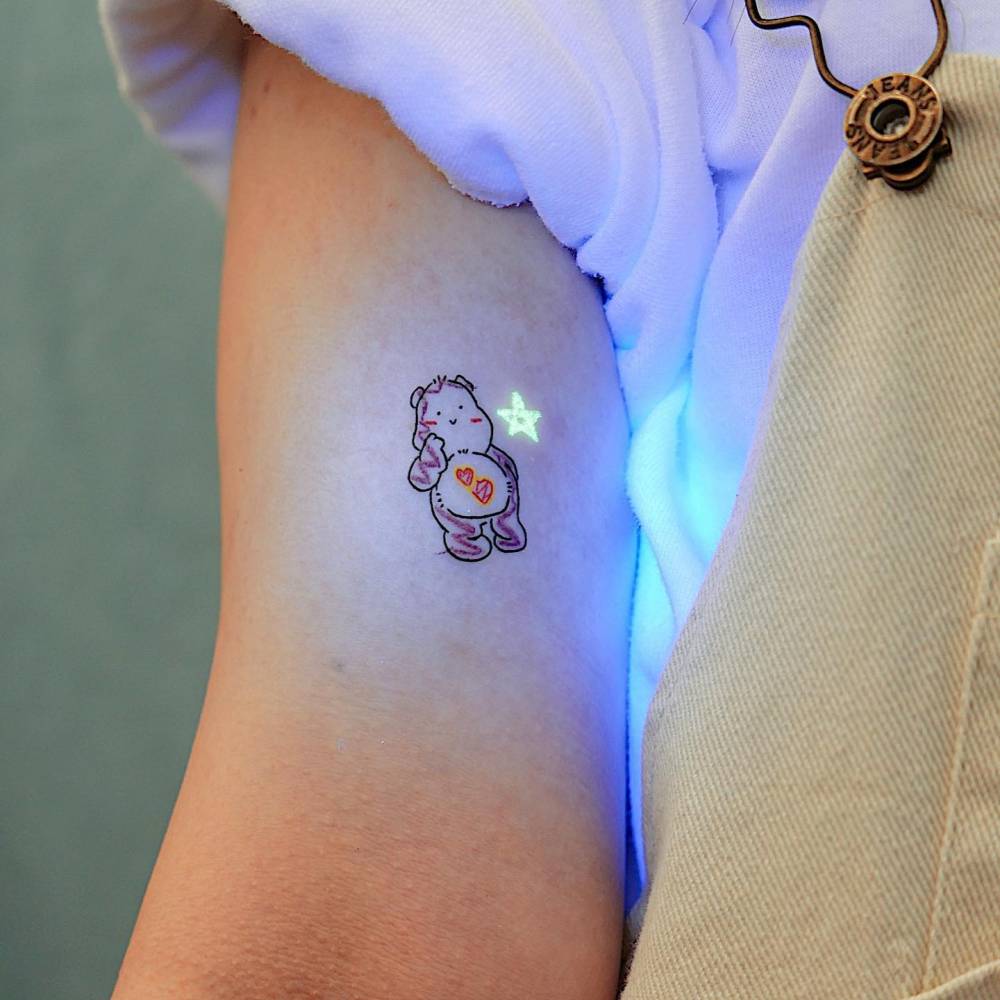 Care Bear tattoo in cartoon style placed on the bicep.