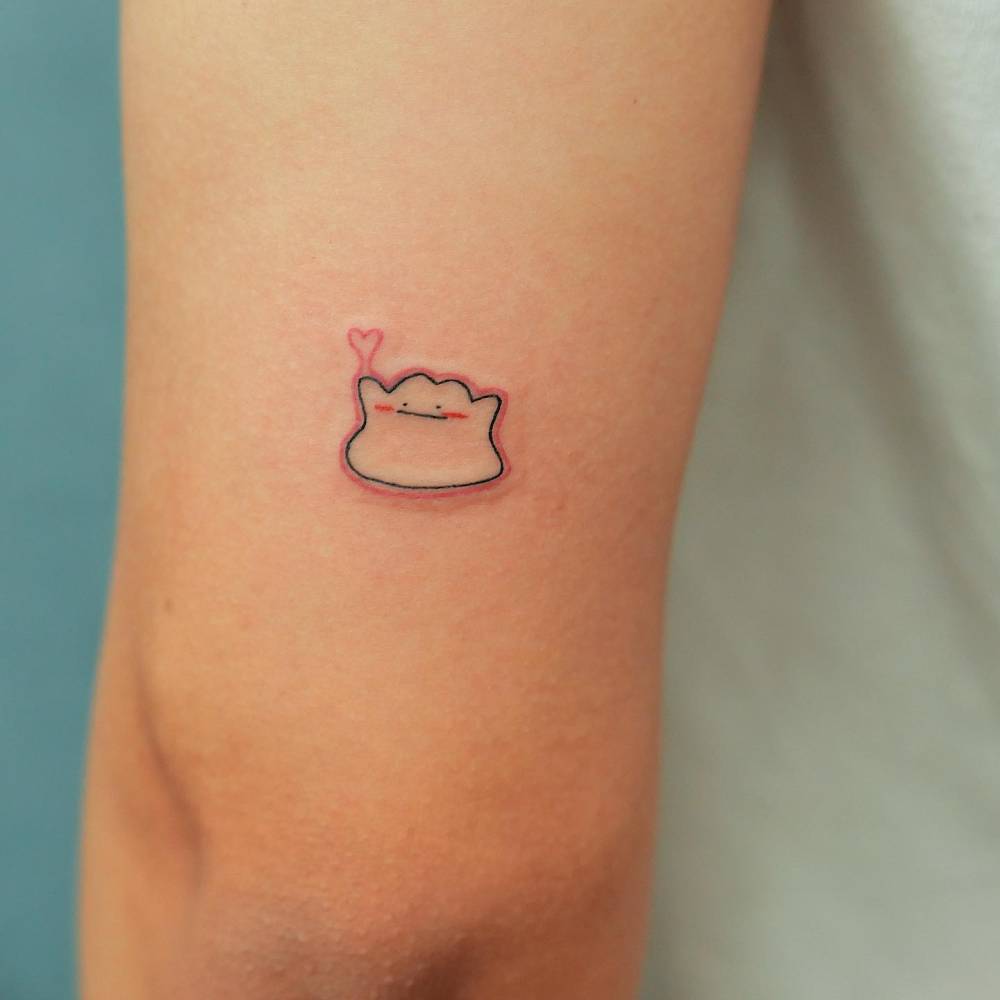 Tiny Ditto tattoo located on the tricep, cartoon style.