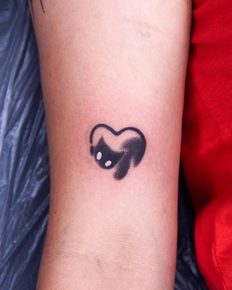Cartoon style black cat heart tattooed on the bicep.