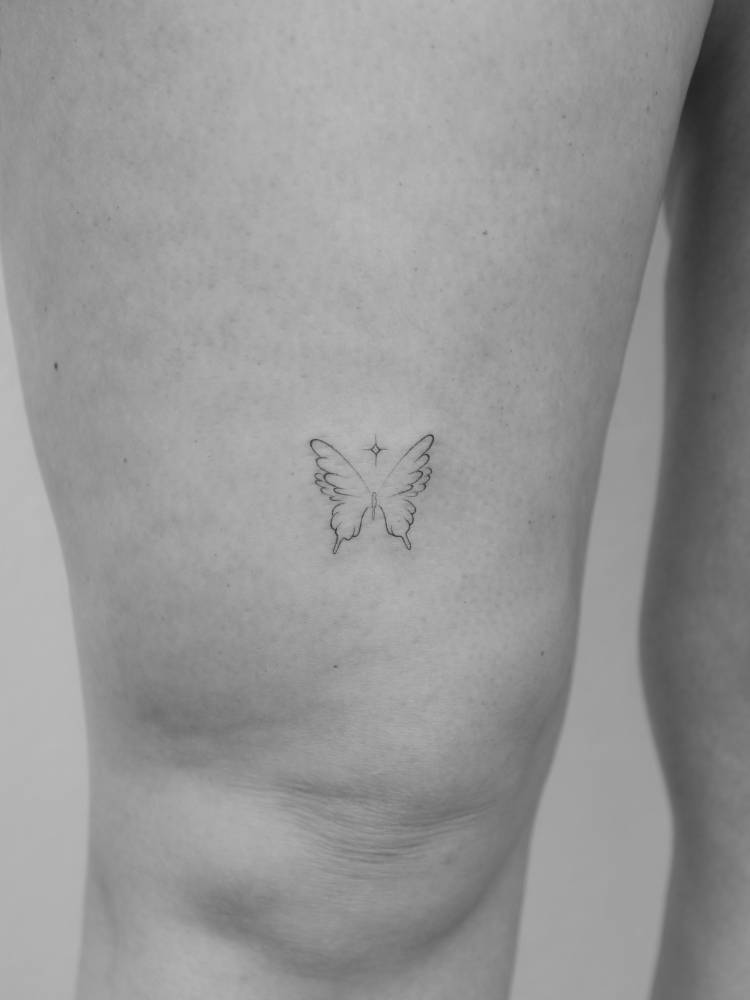Little butterfly in fine line style tattooed on the thigh.