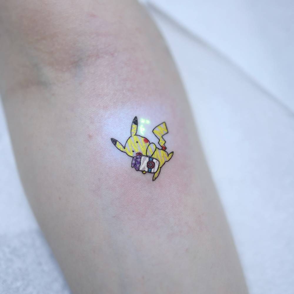 UV ink Pikachu tattoo in ignorant style placed on the inner forearm.