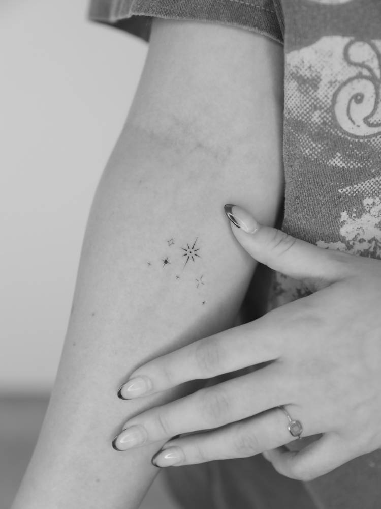 Sparkling stars tattoo located on the inner forearm.