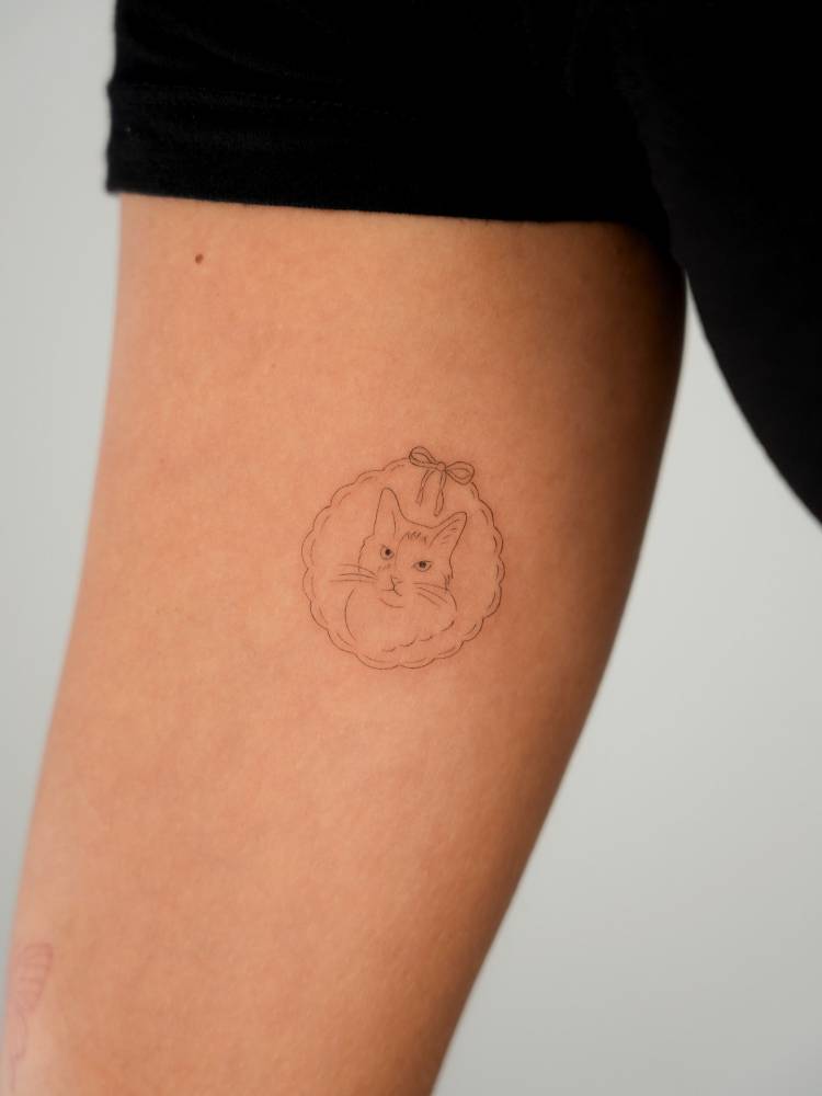 Cat portrait tattoo in fine line style placed on the inner arm.