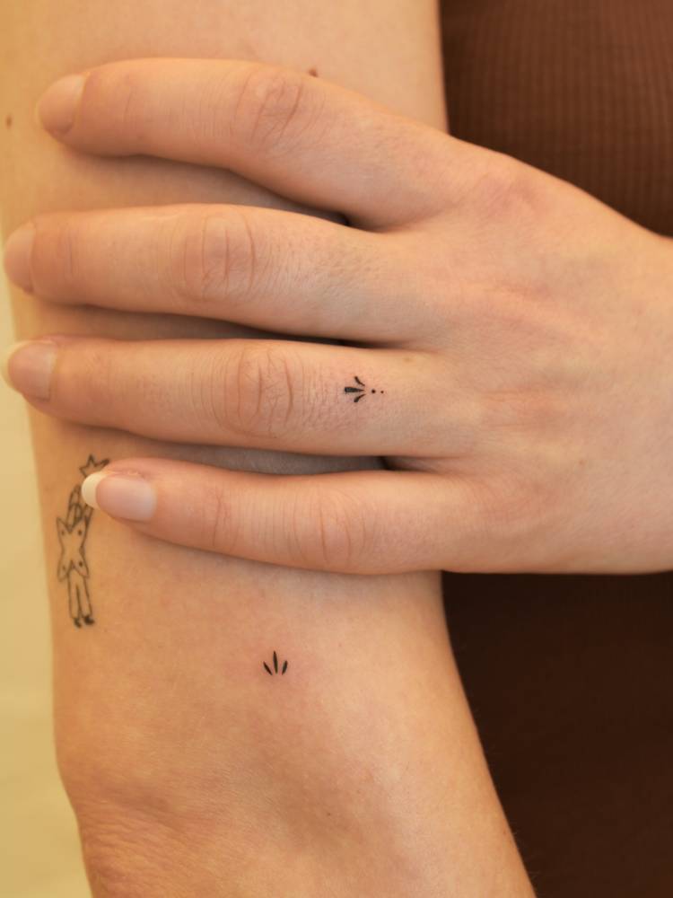 Little minimalistic ornaments tattooed on the upper arm and finger.