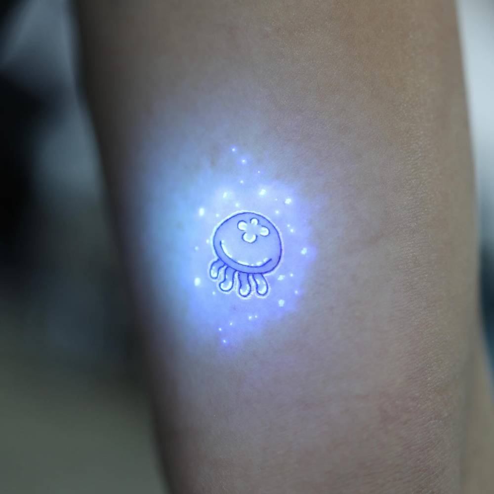 Cute jellyfish tattoo in UV ink located on the inner arm.