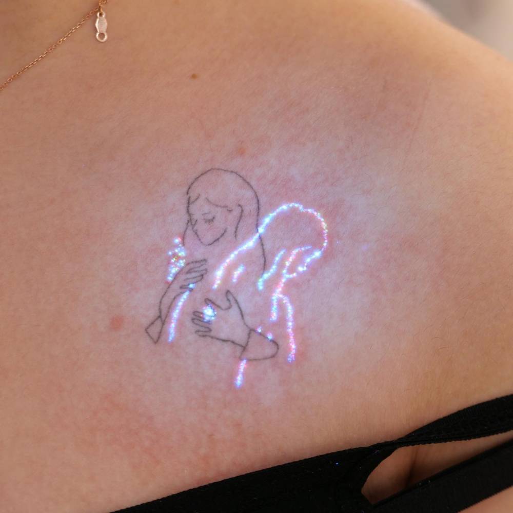 Hug tattoo done with UV ink located on the collarbone.