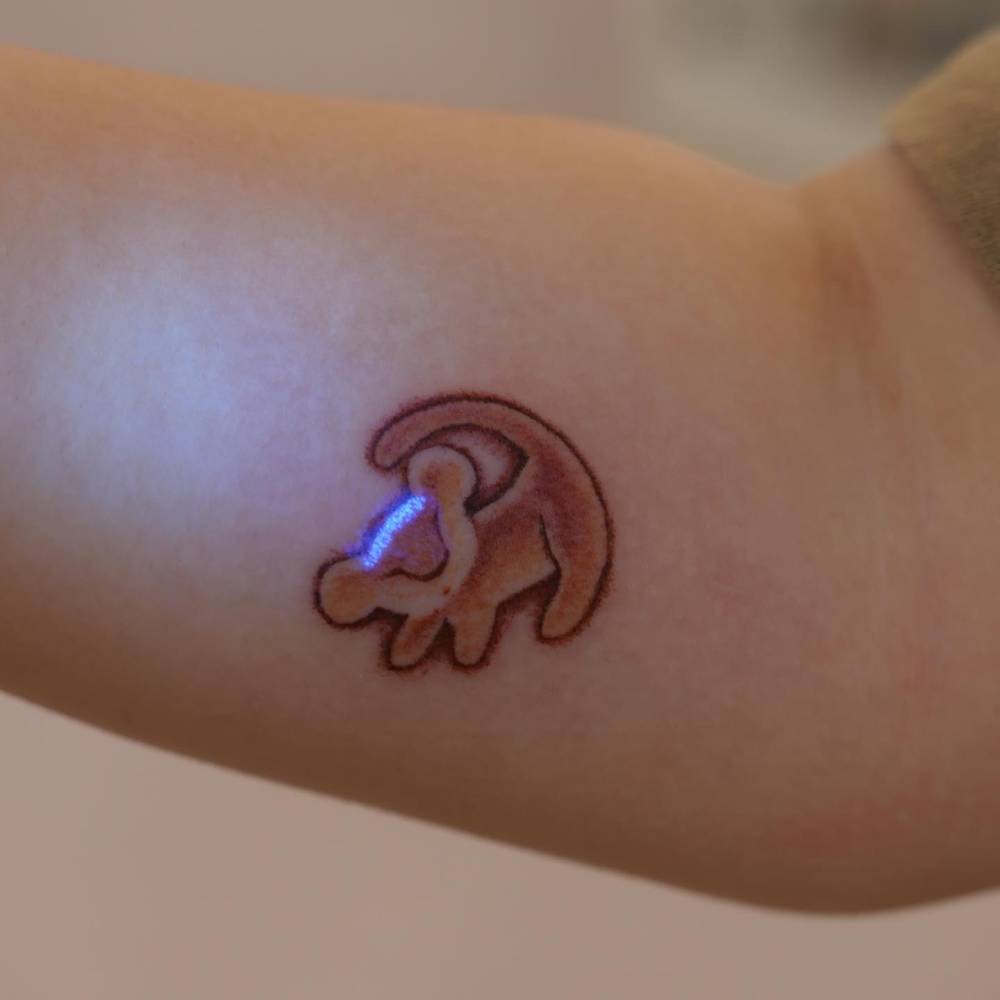 Cartoon style Simba tattoo located on the inner forearm.