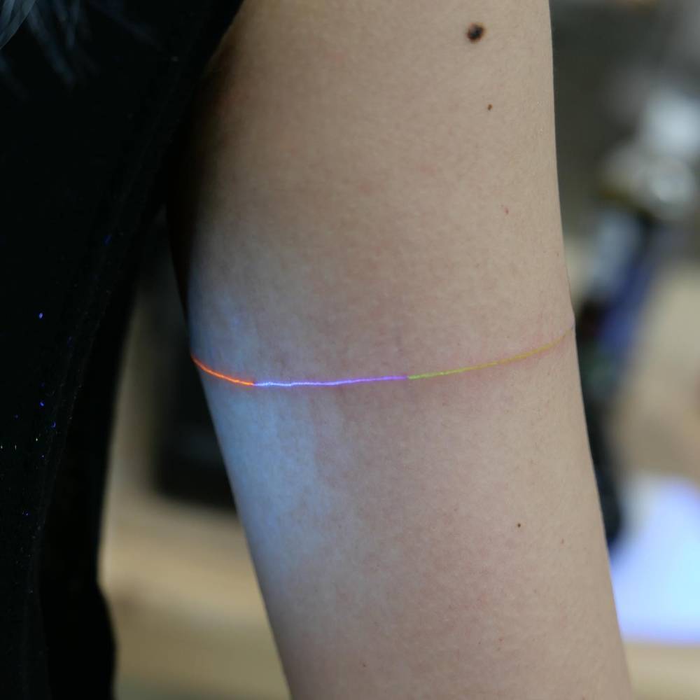 Spectrum armband tattoo in UV ink located on the upper arm.