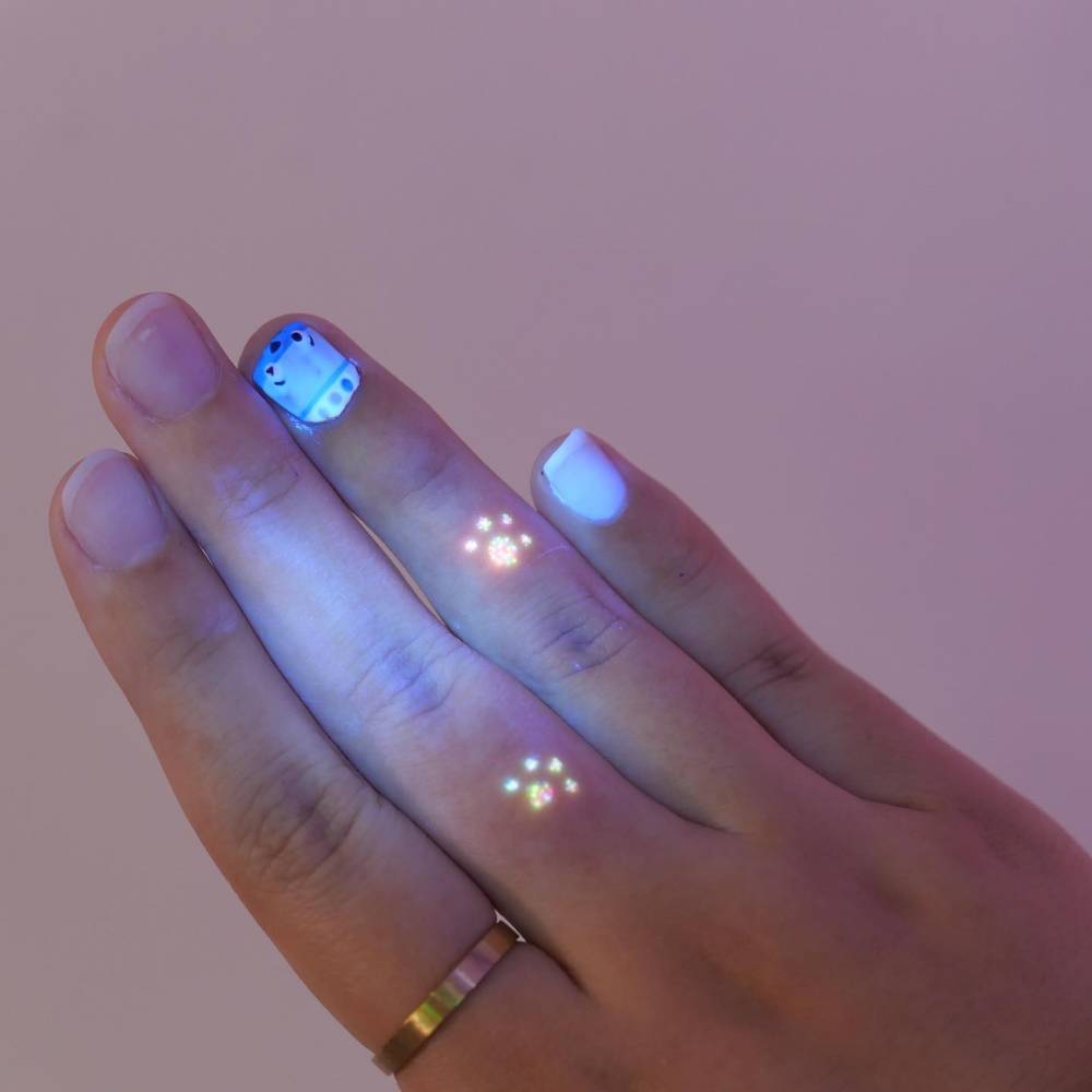 UV ink minimalistic paw prints tattooed on the fingers.