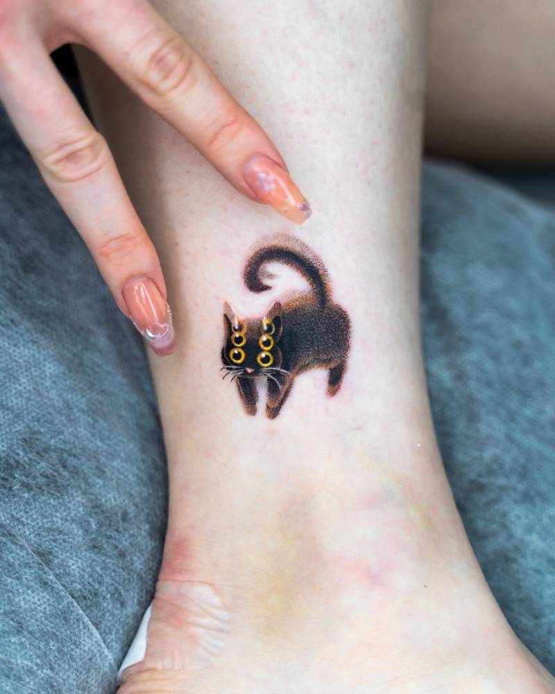 Pop art style black cat tattoo located on the ankle.