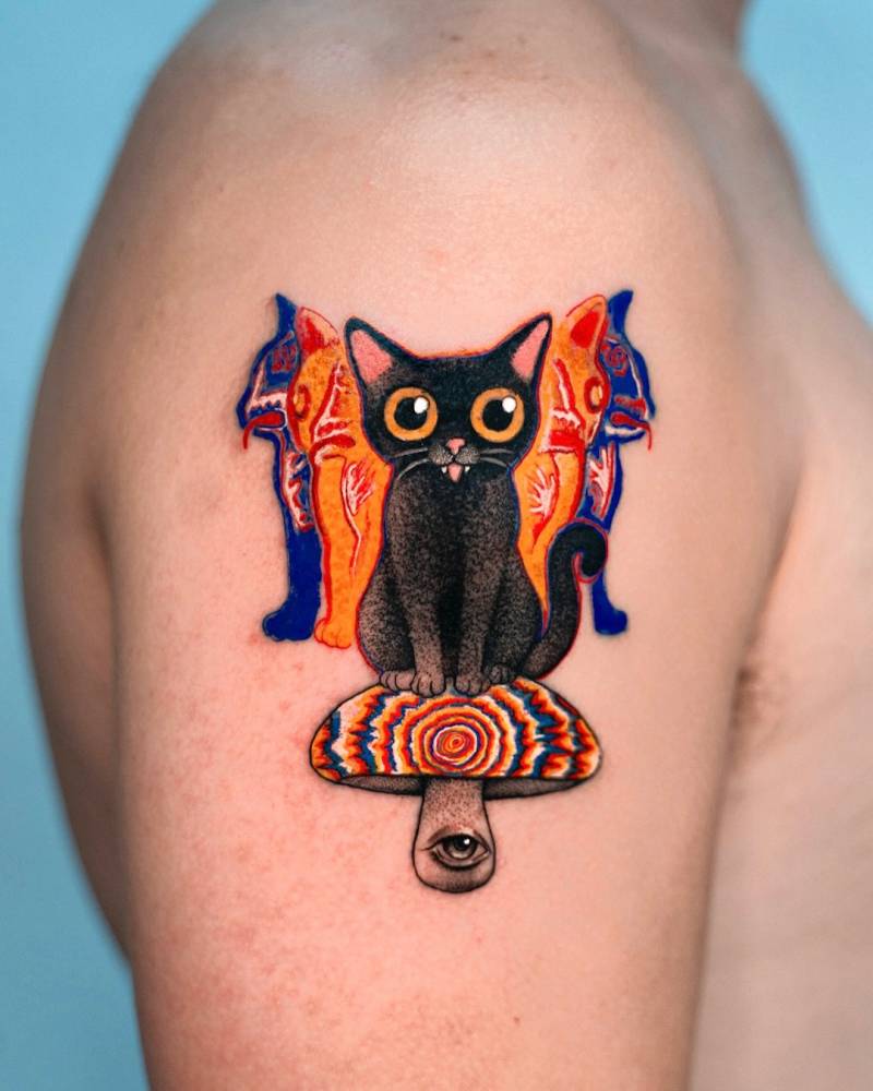 Psychedelic cat and mushroom tattoo located on the upper arm.