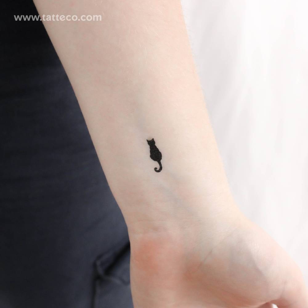 Small minimalistic black cat temporary tattoo located on the wrist.