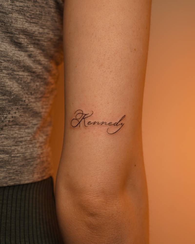 Lettering tattoo of the name "Kennedy" located on the tricep.