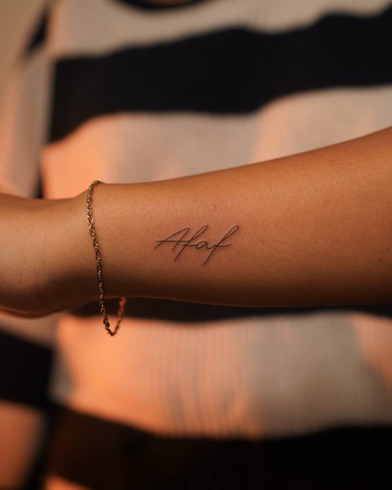 Name "Afaf" lettering tattoo located on the wrist.