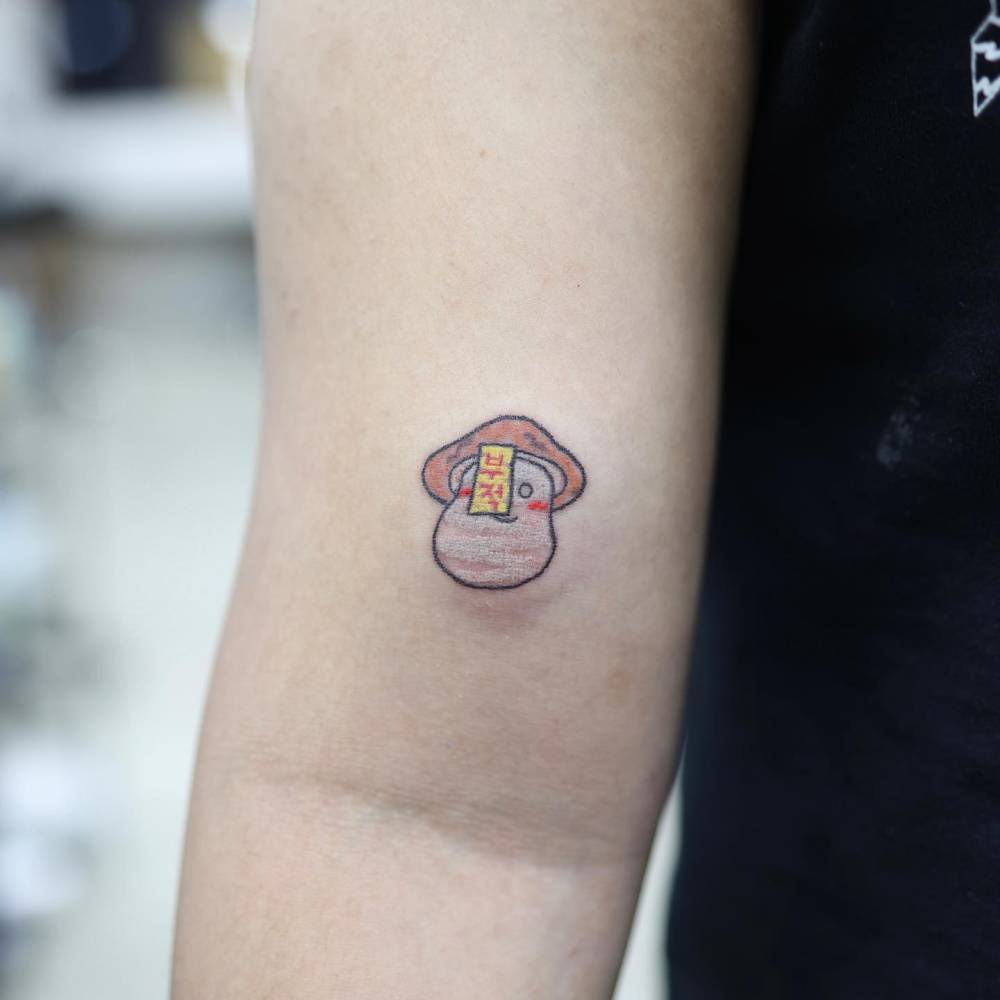 Cartoon style mushroom tattoo located on the bicep.