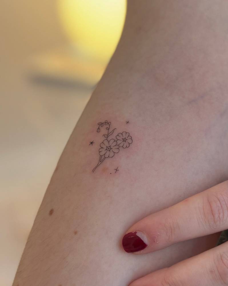 Little flowers tattooed in fine line style, placed on the inner forearm.
