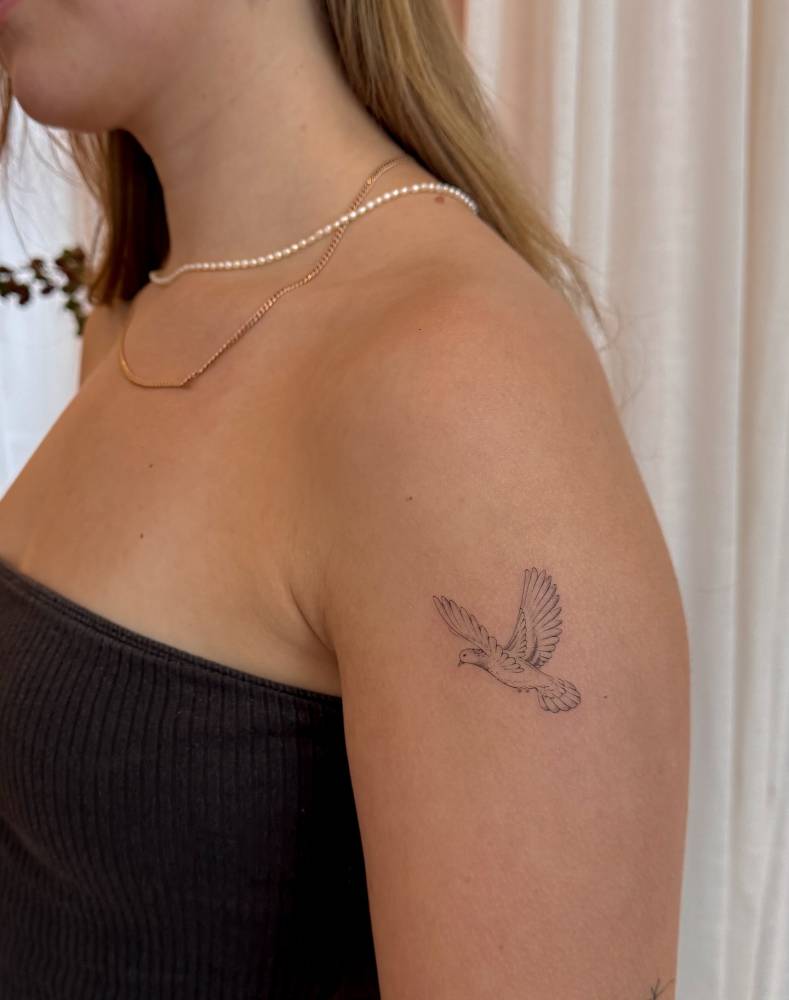 Dove tattoo in fine line style located on the upper arm.