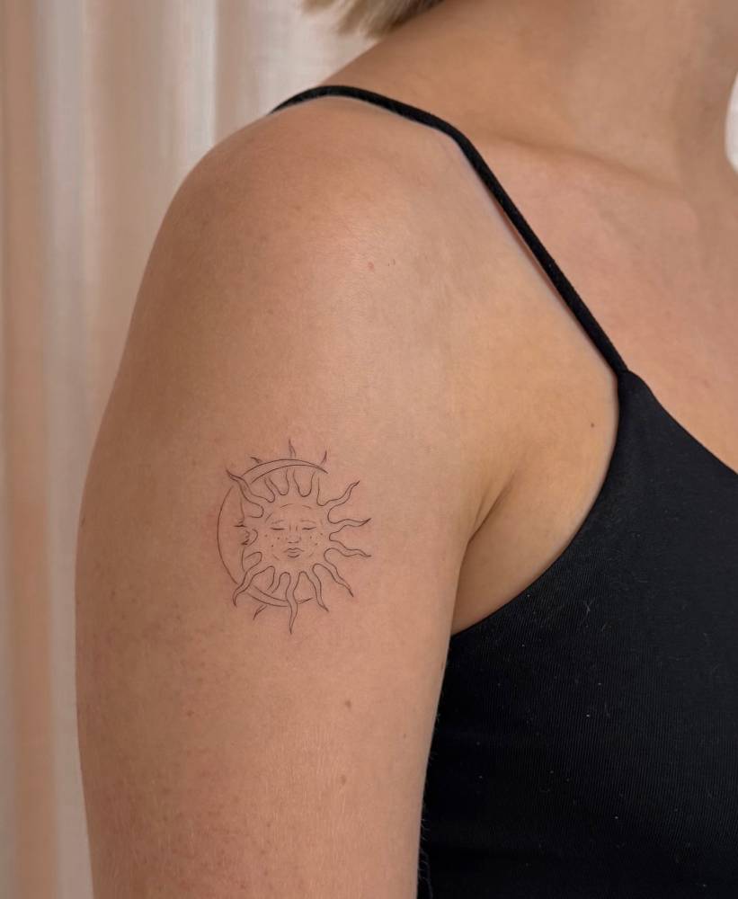 Sun and moon tattoo in fine line style located on the upper arm.