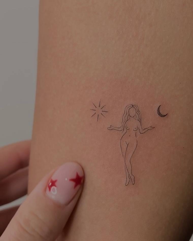 Nude lady and sun and moon tattoo located on the inner arm.