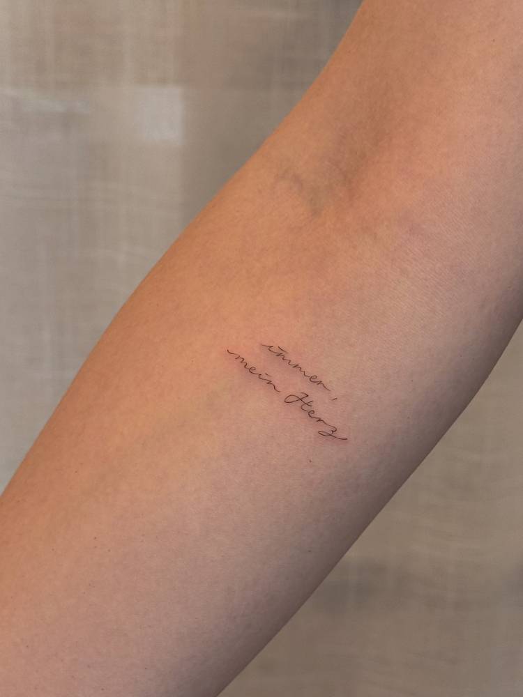 "Immer mein herz" lettering tattoo handwritten on the inner forearm.