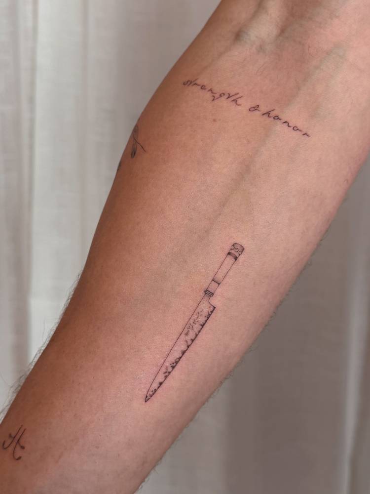 Chef knife tattoo in fine line style located on the inner forearm.