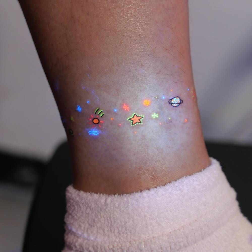 Minimalistic galaxy tattoo in UV ink located on the ankle.