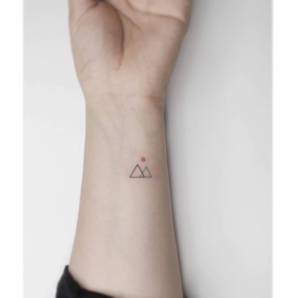 Minimalistic triangle mountains tattooed on the wrist.