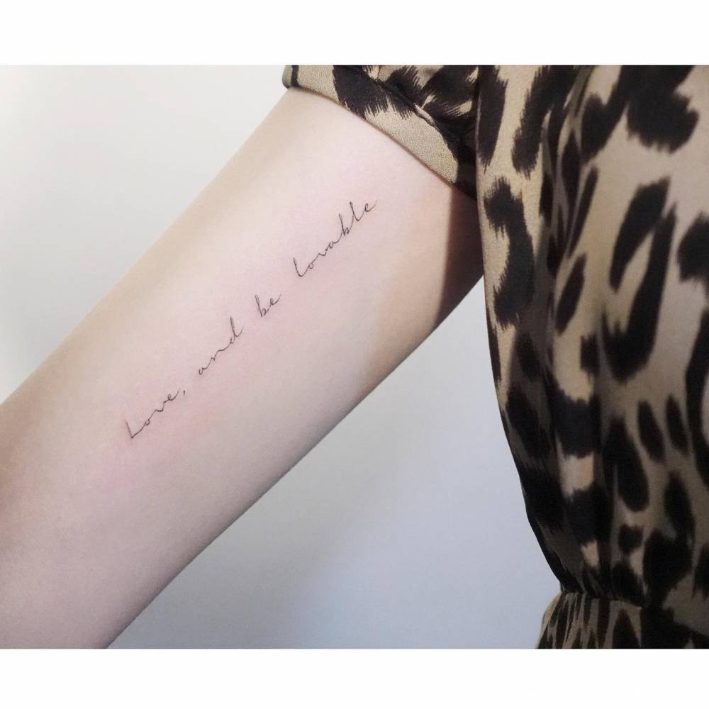 "Love, and be lovable" lettering tattoo handwritten on the inner arm.