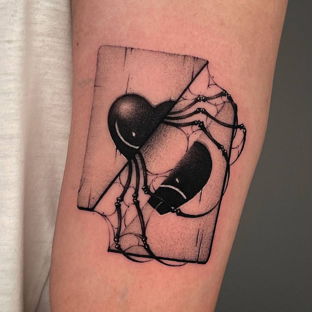 Broken heart and spider tattoo located on the upper arm.