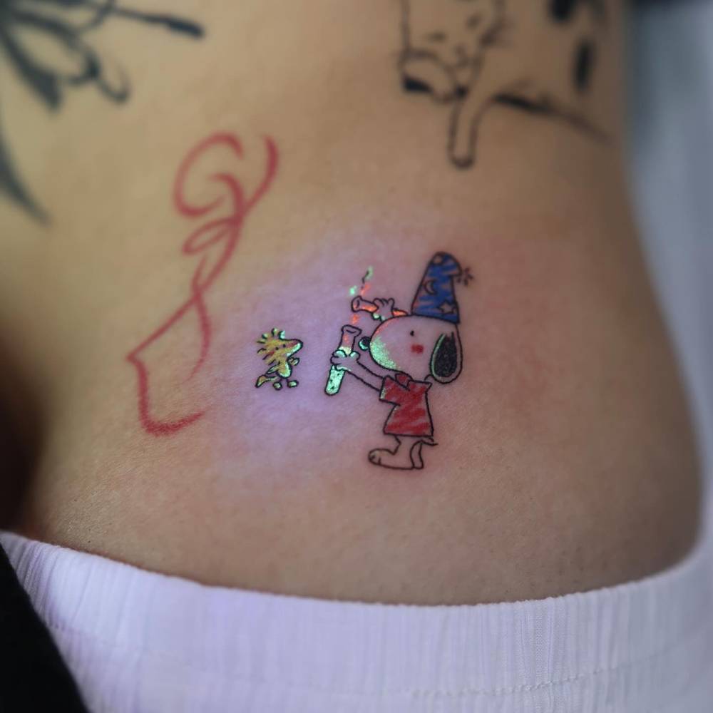 UV ink Snoopy and Woodstock tattoo located on the hip.
