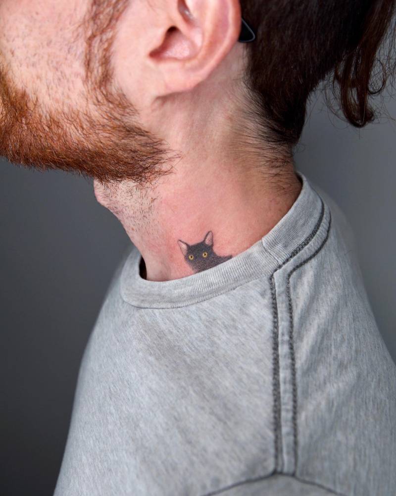 Cute black cat portrait tattoo located on the neck.