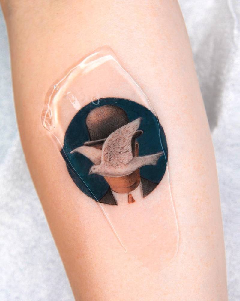 'Man in a Bowler Hat' tattoo located on the inner forearm.