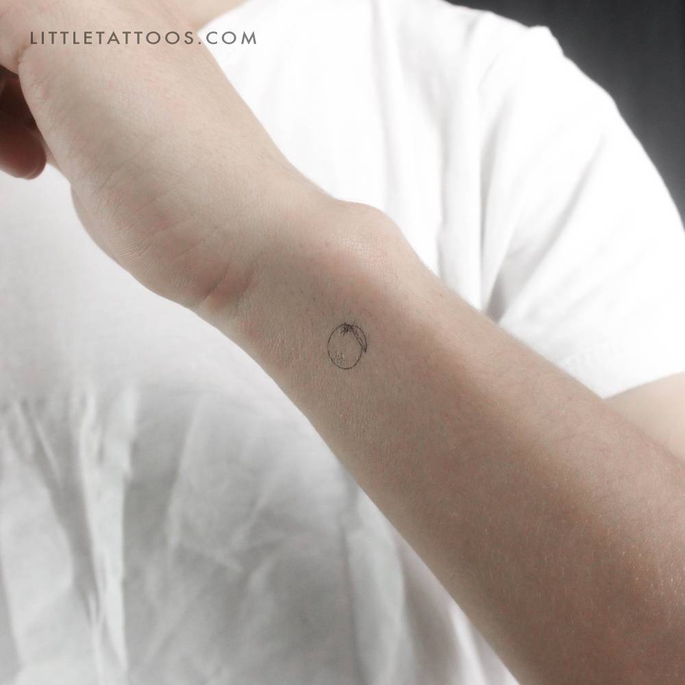 Tiny fine line style orange temporary tattoo placed on the wrist.