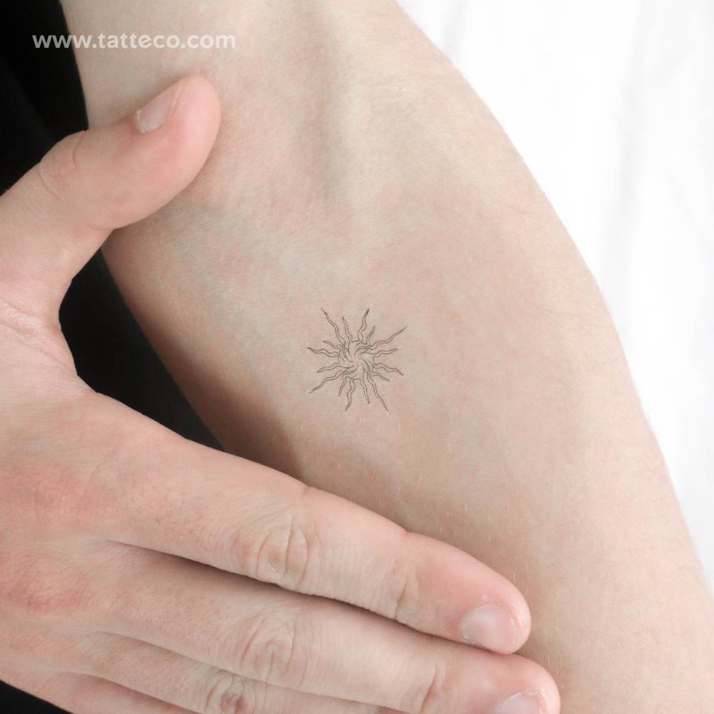 Single line abstract sun temporary tattoo located on the inner forearm.