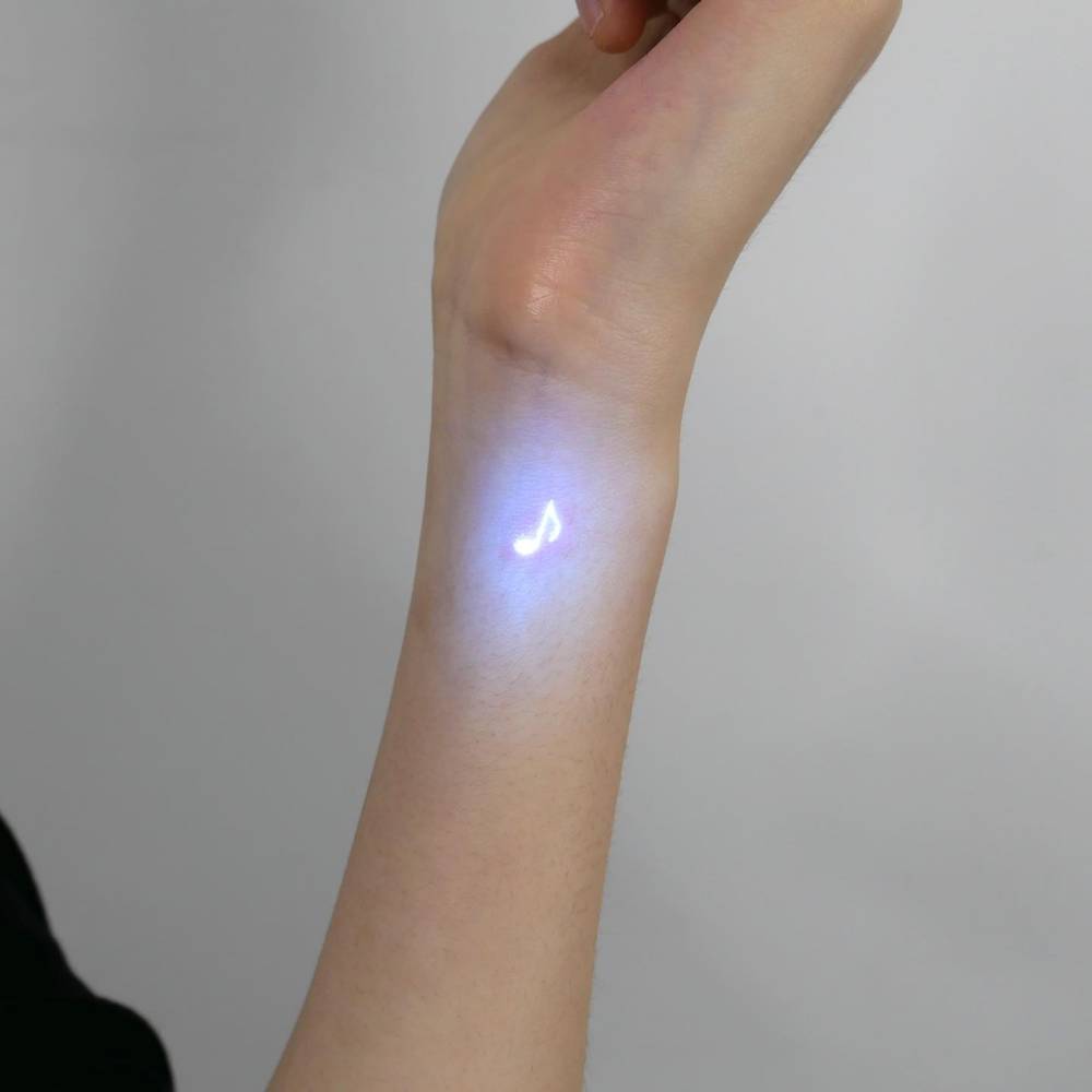 Quaver tattoo in UV ink located on the wrist, minimalistic style.