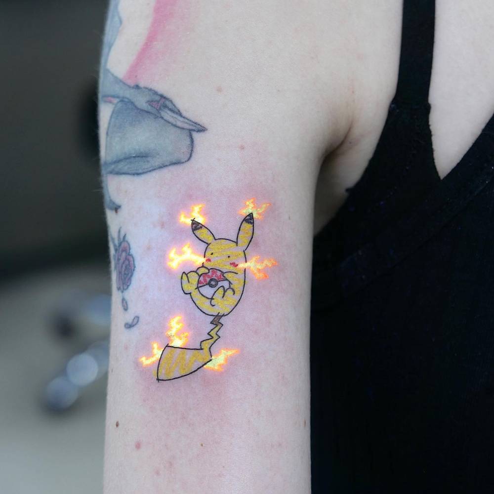 Cute Pikachu tattoo located on the upper arm, cartoon style.