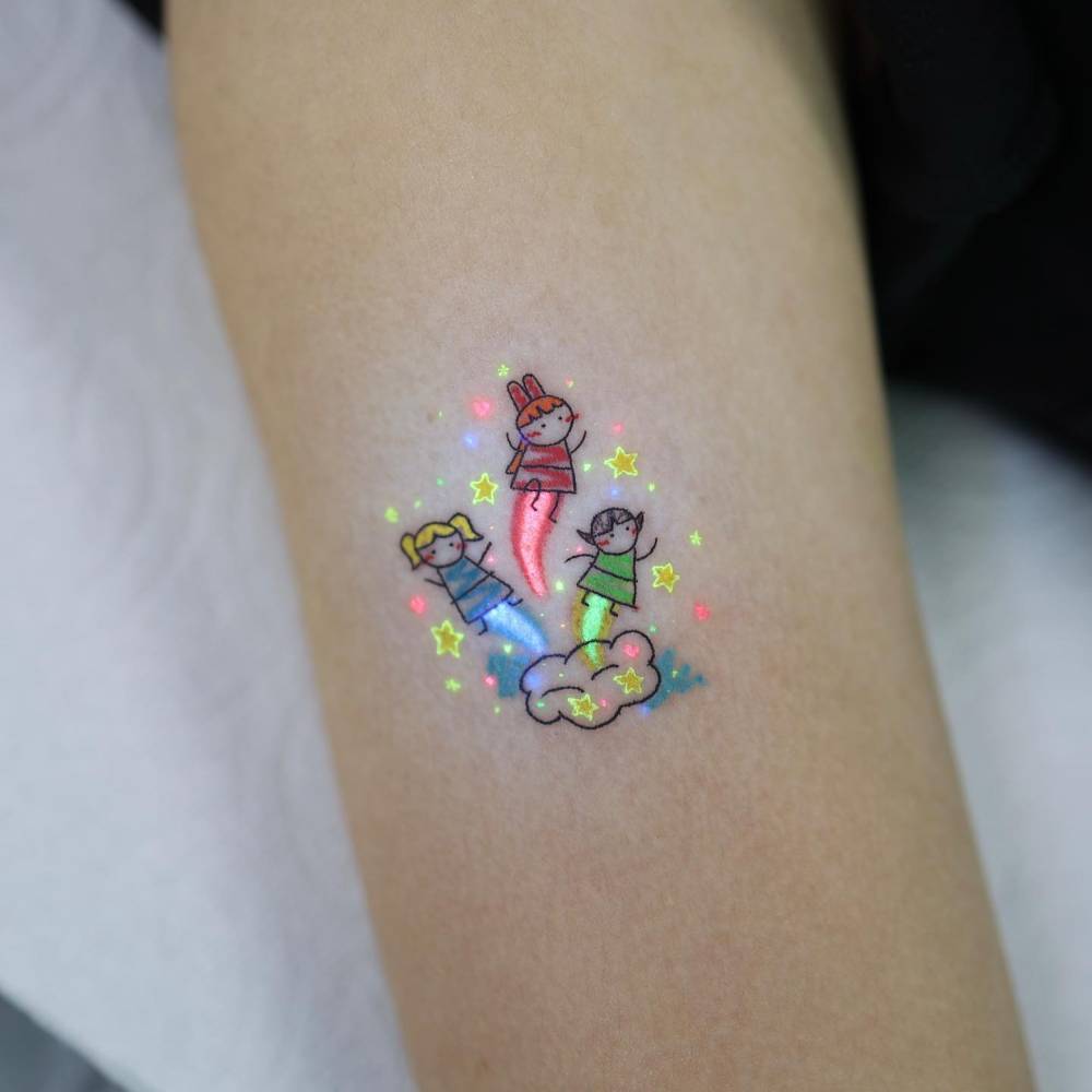 Powerpuff Girls tattoo in cartoon style done on the upper arm.