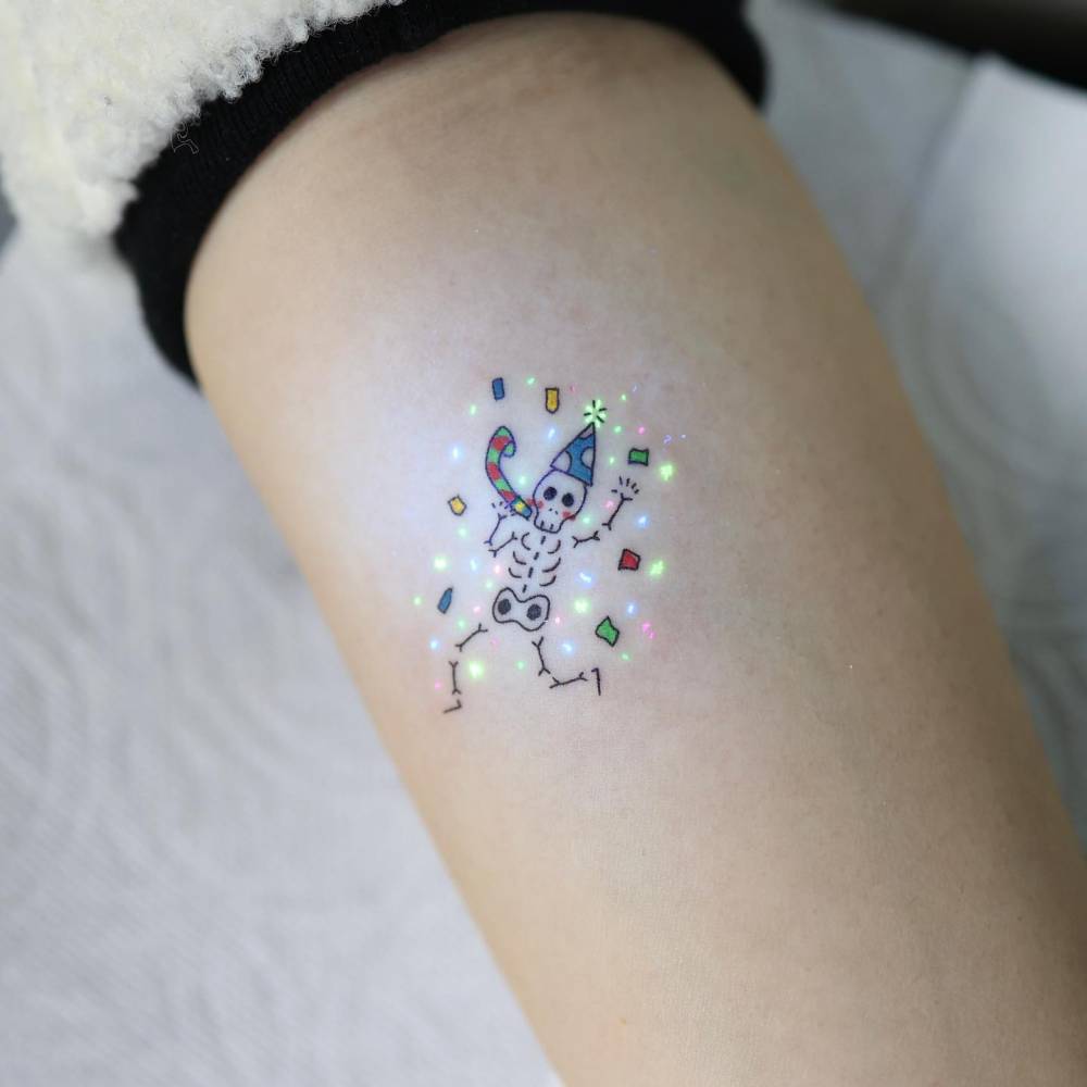 Dancing skeleton tattoo in cartoon style located on the inner forearm.