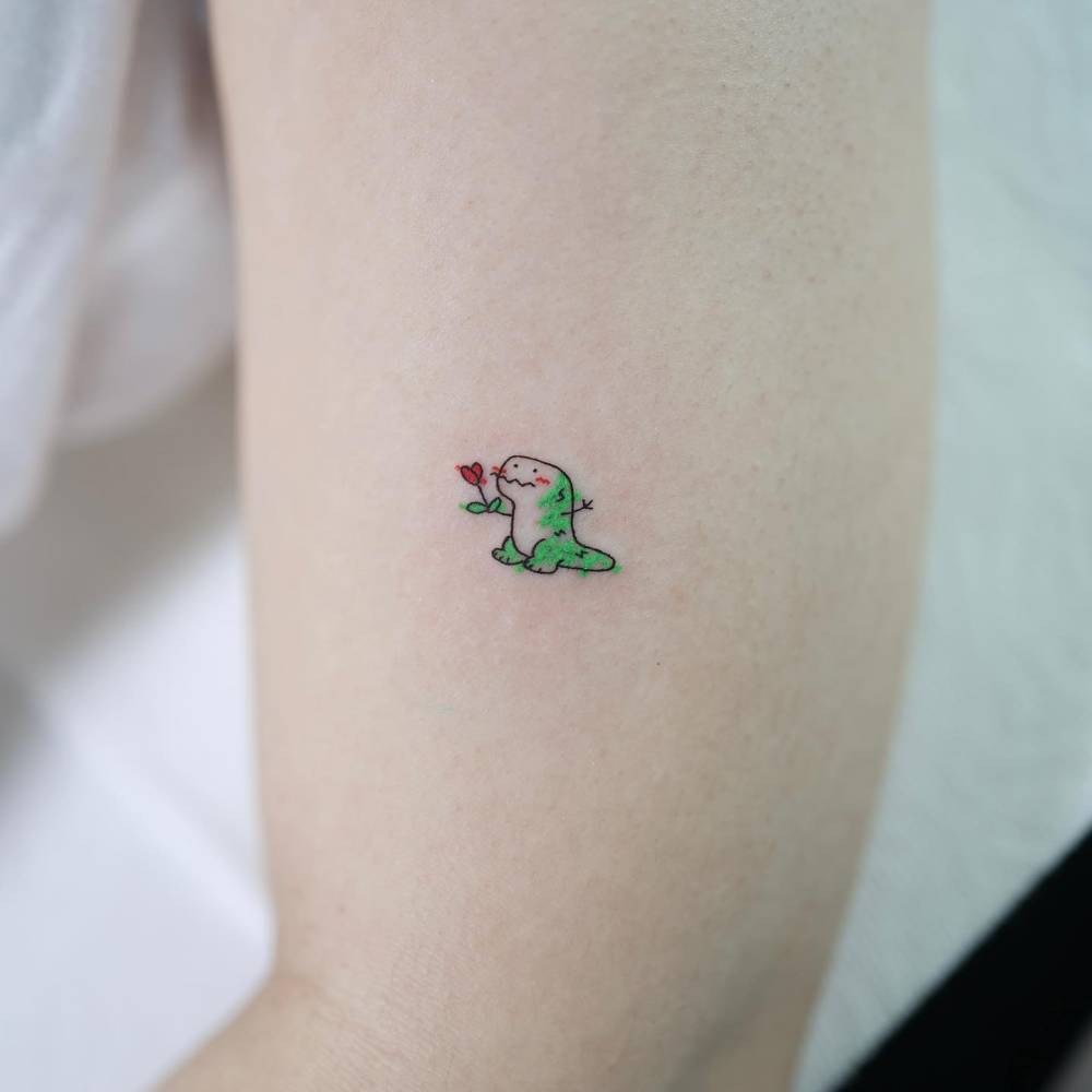 Cute little dinosaur tattooed on the upper arm.