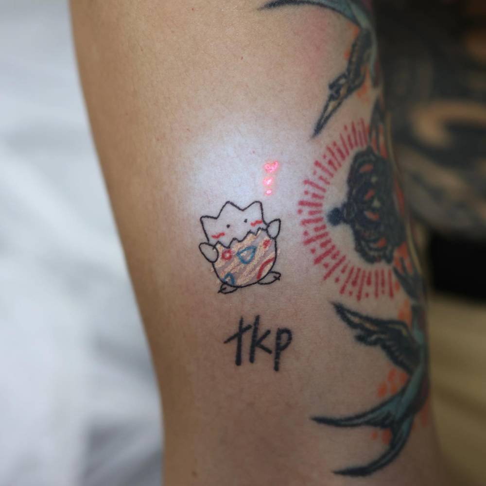 Cartoon style Togepi tattoo in UV ink located on the upper arm.