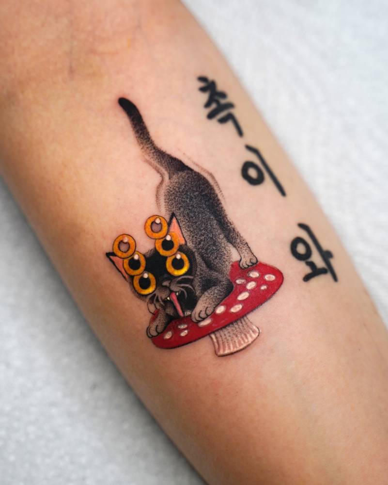 Cat and mushroom tattoo located on the inner forearm.