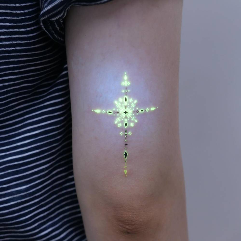 Ornamental design tattoo in UV ink located on the tricep.