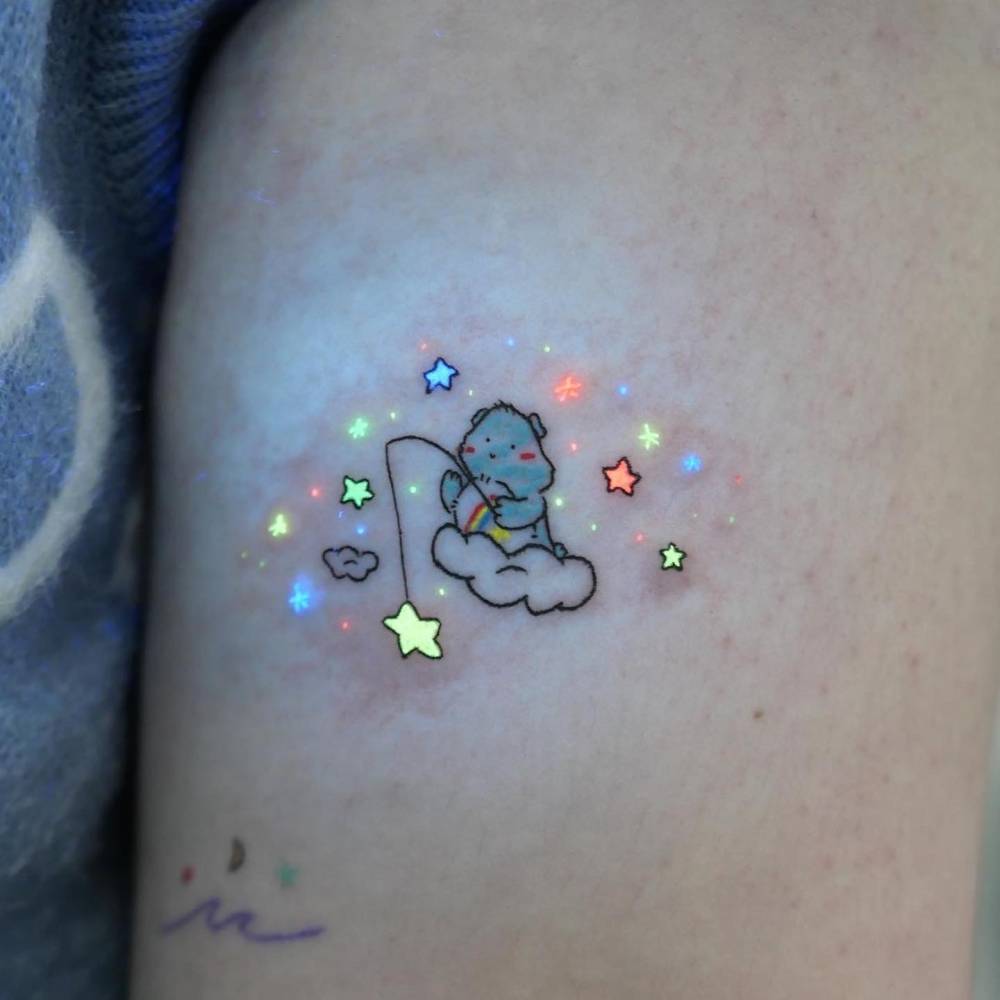 Care Bear tattoo in cartoon style located on the upper arm.